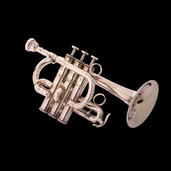 Silver piccolo trumpet with three valves and a mouthpiece, against a black background.