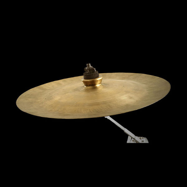 A brass suspended cymbal, or Hängebecken, on a stand against a black background.
